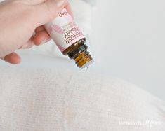 a person is holding an essential oil bottle in their left hand while sitting on a couch