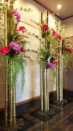 four tall vases with flowers in them on the floor