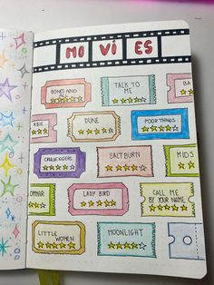 an open notebook with colorful stickers and writing on the pages that read movies,