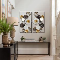 two paintings on the wall above a table in a room with wooden floors and white walls