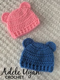 two crocheted hats sitting on top of a blanket