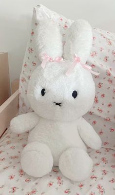 a white stuffed rabbit sitting on top of a bed