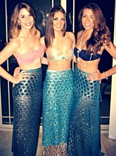 three beautiful young women standing next to each other wearing matching skirts and bra tops with sequins on them