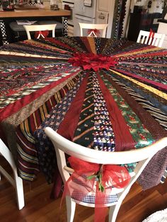 a quilted table cloth on top of a white dining room chair with red ribbon