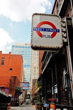 the sign for fleet street pub is hanging from the side of the building in front of it