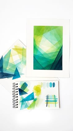 three pieces of paper with different colors and shapes on them next to a spiral notebook