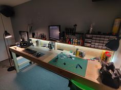 a desk with many items on it in a room that is lit up by lights