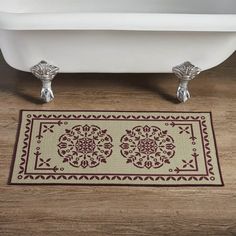 a bath tub sitting on top of a wooden floor next to a white toilet and rug