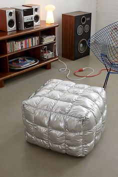 an inflatable chair sits on the floor next to bookshelves and speakers