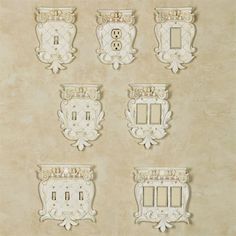 four white switch plates mounted to the side of a wall with ornate designs on them