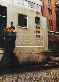 two people standing on the side of a train