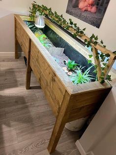 there is a fish tank with plants in it on the side of the table,