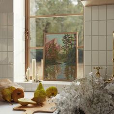 some pears are on a cutting board in front of a window with a painting