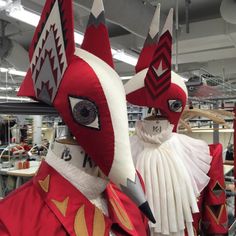 two red and white masks are on display in a storeroom with other items behind them