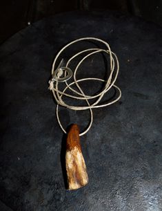 a piece of wood sitting on top of a stone floor next to a rope and hook