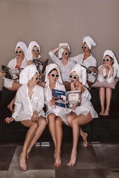 a group of women sitting on top of a couch wearing white robes and holding books