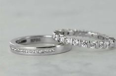 two white gold wedding rings with diamonds on them, sitting side - by - side