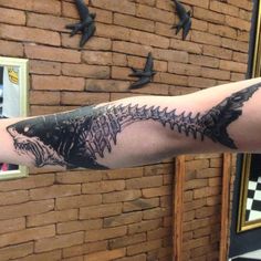 a man with a tattoo on his arm has a fish skeleton in the shape of a shark