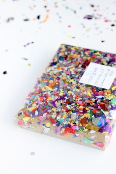 a notebook covered in confetti and sprinkles on a white surface