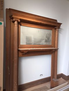 an old fashioned fireplace in a room with white walls and wood trimming on the mantle