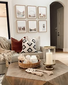 a living room with pictures on the wall, candles and other items sitting on a coffee table