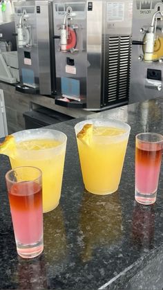 three glasses filled with drinks sitting on top of a counter