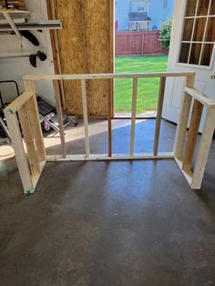 the inside of a house being built with wooden framing and doors opened to reveal a yard