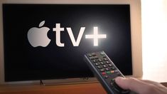 a person holding a remote in front of an apple tv