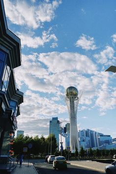 cars are driving down the street in front of tall buildings and a tower with a clock on it