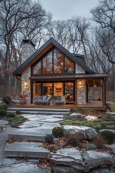 a small cabin with stone steps leading to the front door and covered patio area, surrounded by trees