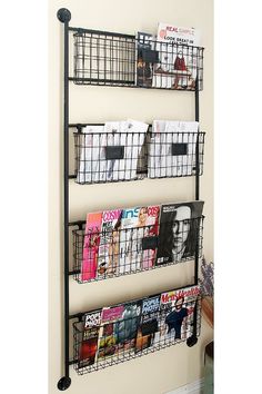 three wire baskets are hanging on the wall next to magazines and magazines in bins