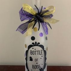 a bottle with a purple bow on it that says bottle of boos in front of a white wall