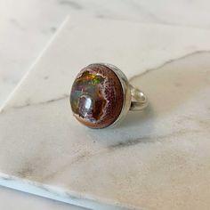 A colorful, very high quality, raw Mexican Fire Opal has a bright rainbow colored flash. It is hand set into Sterling Silver bezel and sits on a simple half-round Sterling Silver band. Ring is a size 7This ring is one of a kind and can not be re-sized. Please message me about other stones I have on hand for custom orders. The stone 20mm +++Fire Opal was born in fire, in the ancient volcanoes of Mexico. Fire opal forms when water seeps into silica-rich lava, filling seams and hollows. Fire Opal i