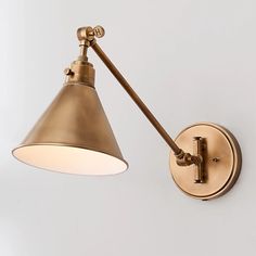 an antique brass swing arm wall light with a white shade