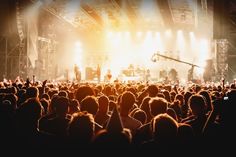 a large group of people in front of a stage with bright lights on the side