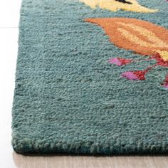 a close up of a rug on the floor with flowers and birds painted on it