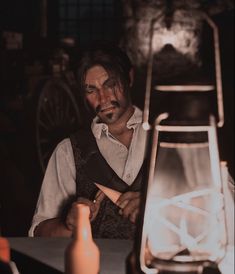 a man sitting at a table next to a lantern