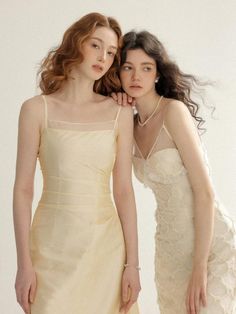 two women standing next to each other in dresses