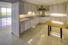 an empty kitchen with marble counter tops and white cabinets, along with sliding glass doors