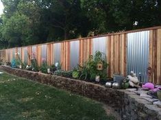 a wooden fence next to a garden with potted plants