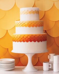 a three tiered cake sitting on top of a table next to plates and cups