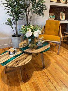 two tables sitting on top of a hard wood floor next to a potted plant