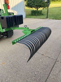 a large green plow sitting on top of a cement road