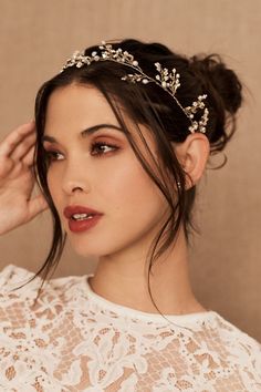 a woman wearing a tiara with flowers on it's head and her hair in a bun