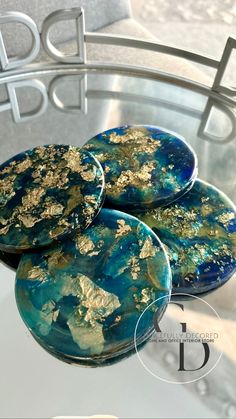 three blue and gold coasters sitting on top of a glass table