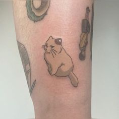 a cat tattoo on the leg of a person's leg, with other items in the background