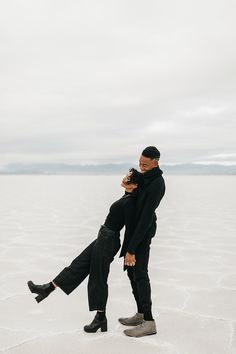 a man and woman are standing in the middle of an empty salt flat with their arms around each other