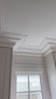 an empty room with white walls and trimmings on the ceiling, along with a window