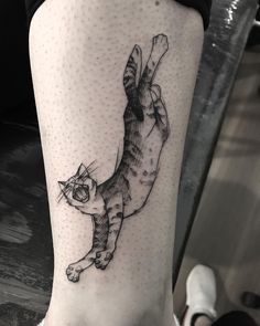 a black and white cat tattoo on the right leg, it looks like he is falling off