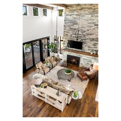 an aerial view of a living room with wood flooring and stone fireplace in the center